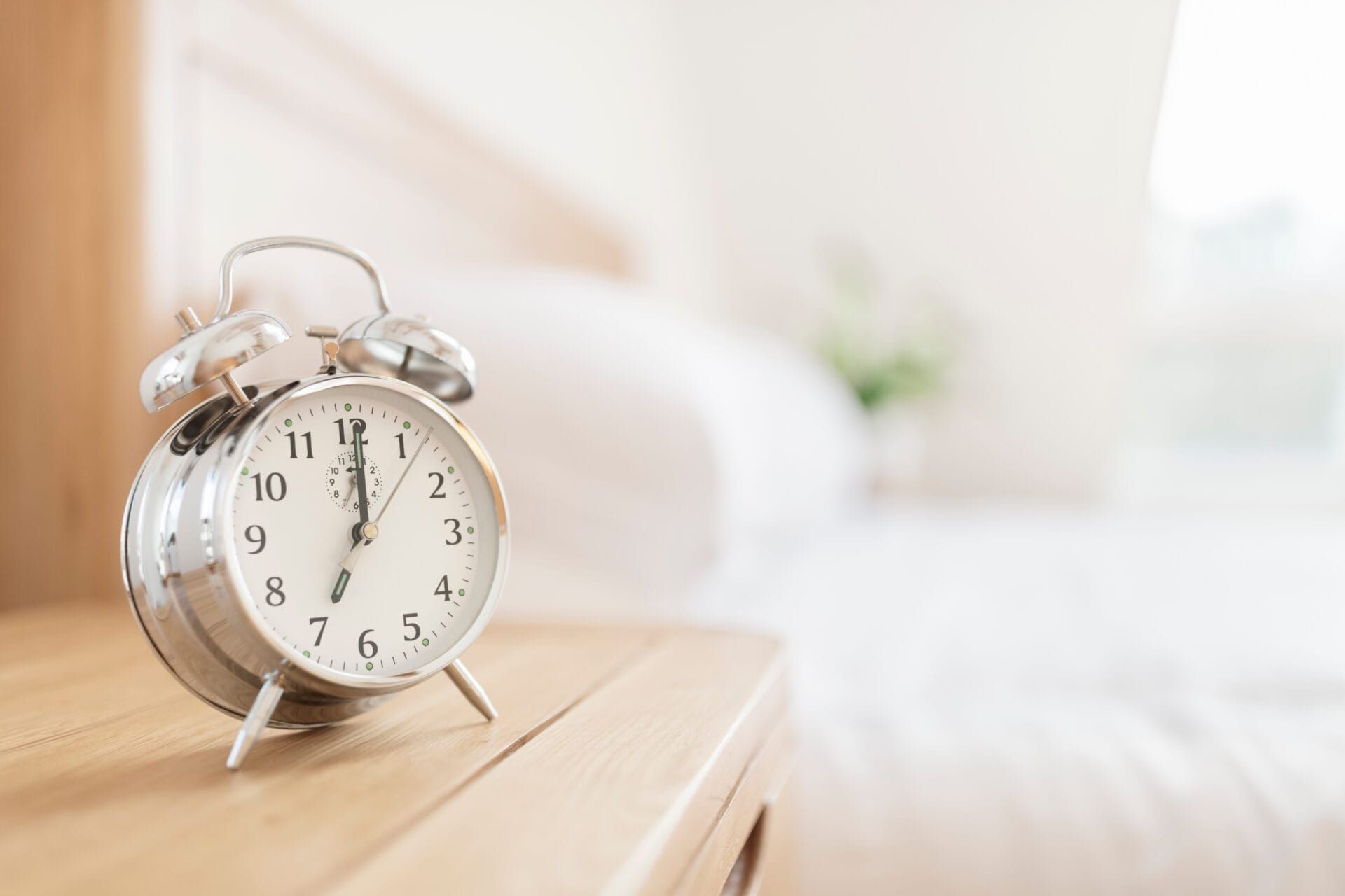 Alarm clock showing 7am on a bedroom nighstand.