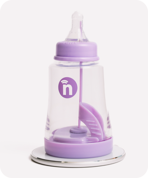 The nfant® Thrive Smart Bottle is shown on its charger stand.